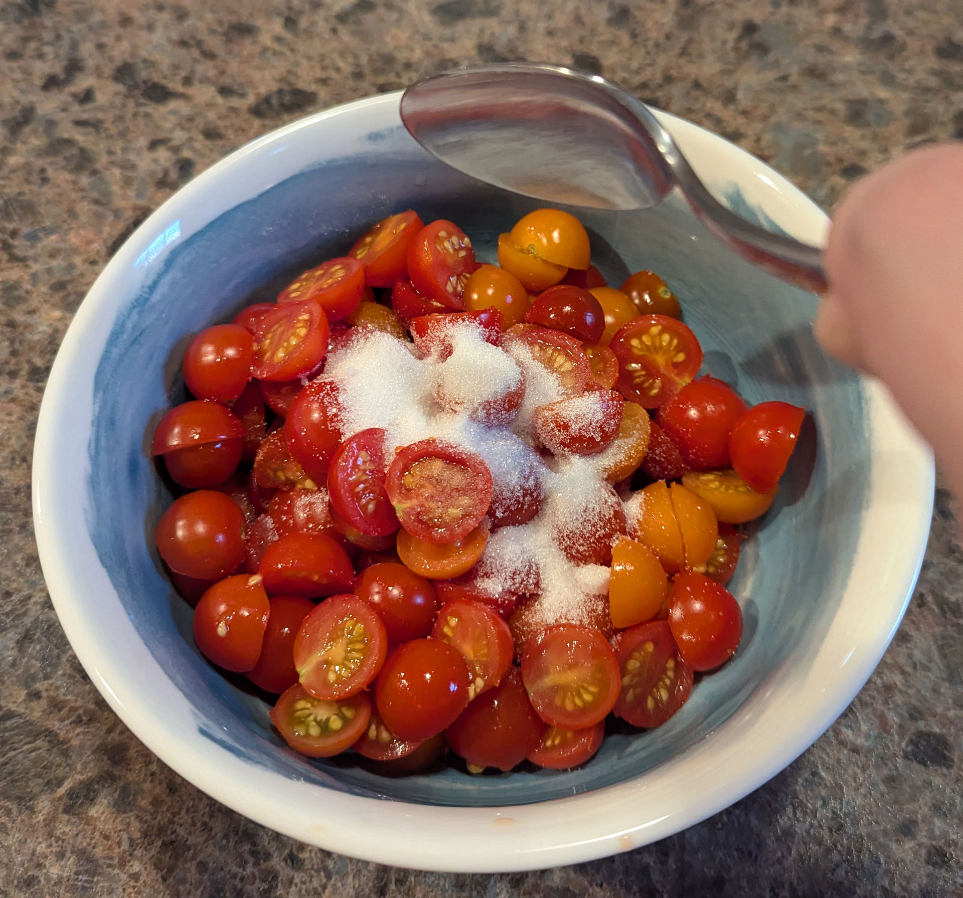 A bowl of cherry tomatoes, with sugar in it.